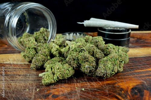 One ounce marijuana with jar, joints and grinder against black background photo