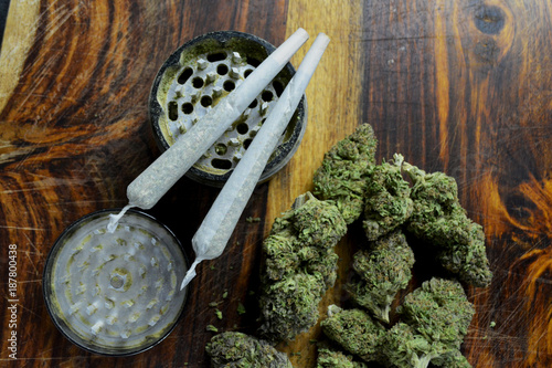 Marijuana joints and buds and grinder on wooden board