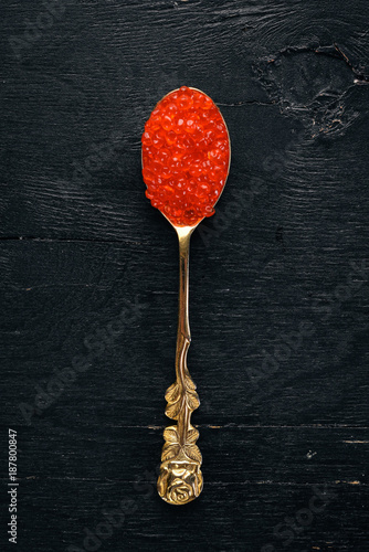 Spoon with red caviar on a wooden background. Top view. Free space for text.