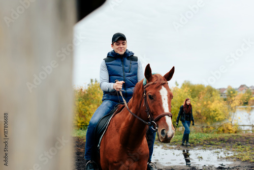 man learns riding a horse in autumn in a rural landscape © ShevarevAlex