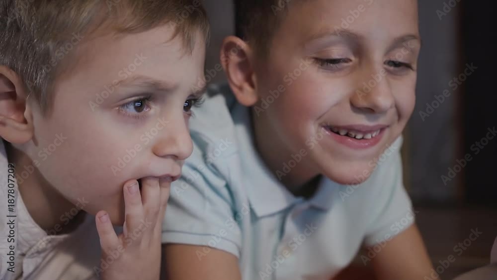 Close up of two handsome little guys smiling and looking at something interesting on the laptop. Technology, laptop, children Close up of two handsome little guys smiling and looking at something interesting on the laptop. Technology, laptop, children