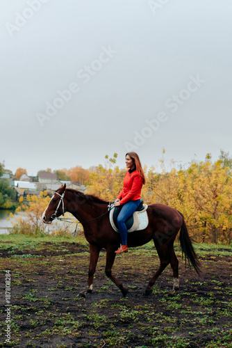 beautiful girl rides a horse in a village in the fall