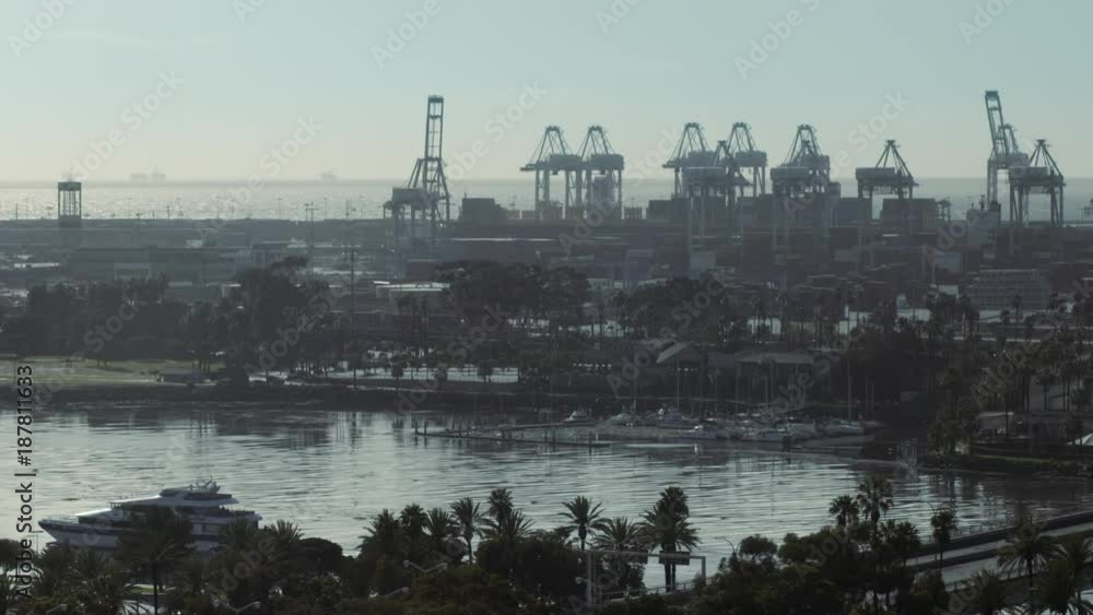 Massive cargo cranes line the docks at the Port of Long Beach in Los Angeles, CA. Early morning view with strong backlight and haze, HD. Massive cargo cranes line the docks at the Port of Long Beach in Los Angeles, CA. Early morning view with strong backlight and haze, HD.