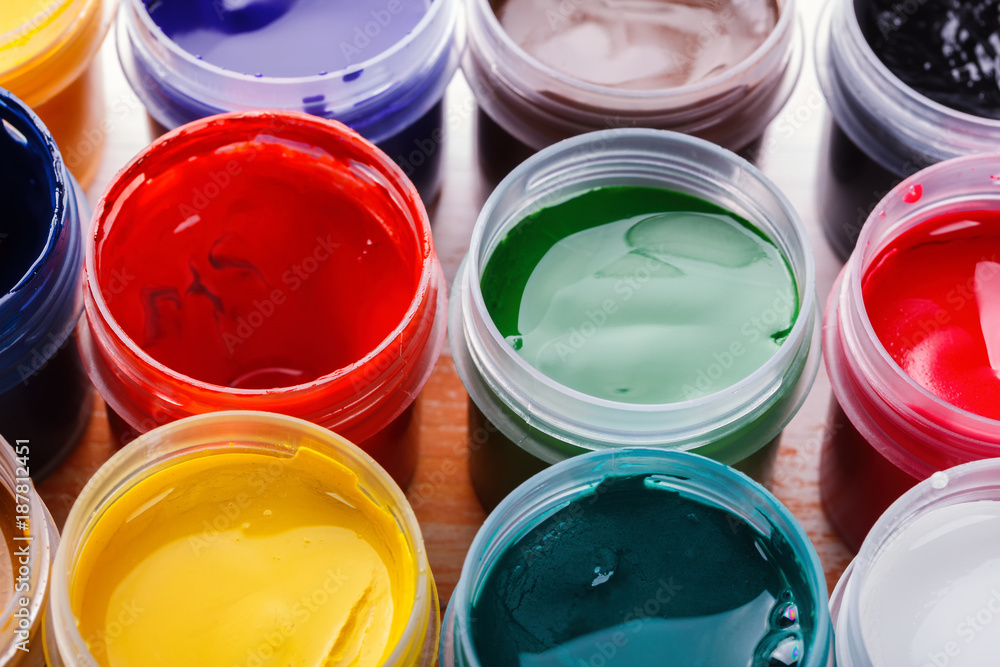 Plastic cans of multi-colored gouache on a wooden painted table Plastic cans of multi-colored gouache on a wooden painted table