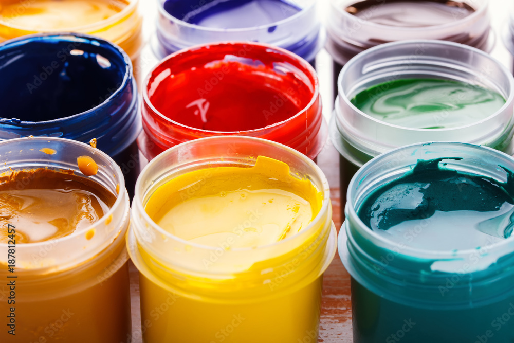 Plastic cans of multi-colored gouache on a wooden painted table Plastic cans of multi-colored gouache on a wooden painted table