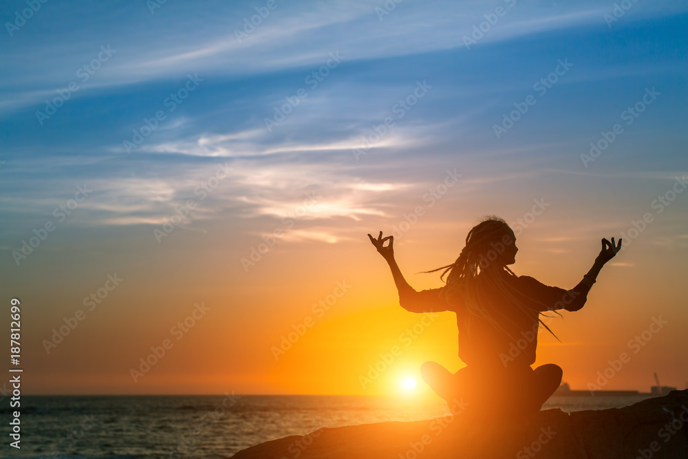 Yoga woman silhouette. Meditation on the Ocean during amazing sunset. Healthy lifestyle.