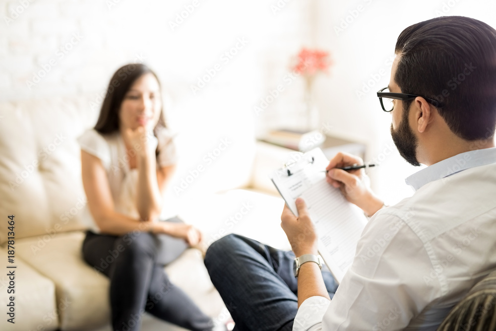 Psychologist making notes during a session with woman patient Psychologist making notes during a session with woman patient