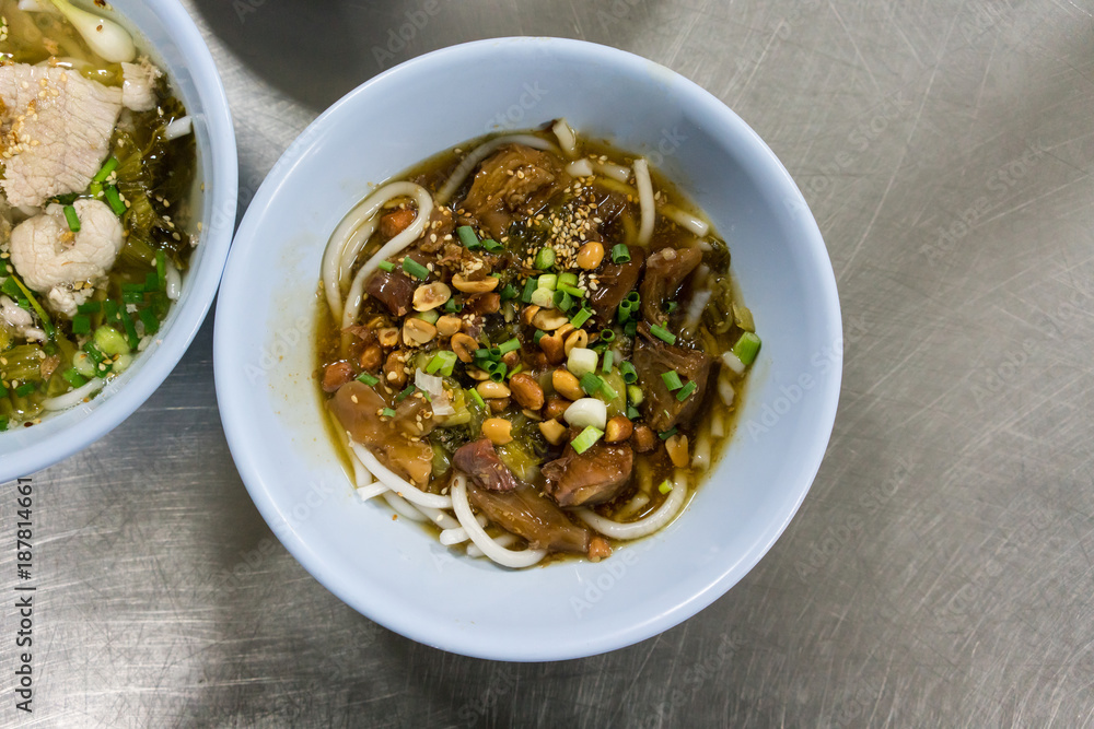 A bowl of Hainan rice noodle with braised beef in Thai style on stainless steel table.