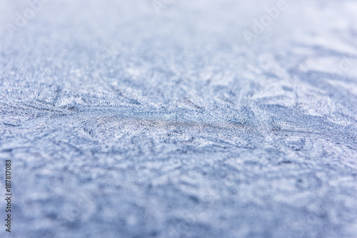 Macro closeup of frost snow ice crystals on window glass of car surface showing pattern, texture and bokeh