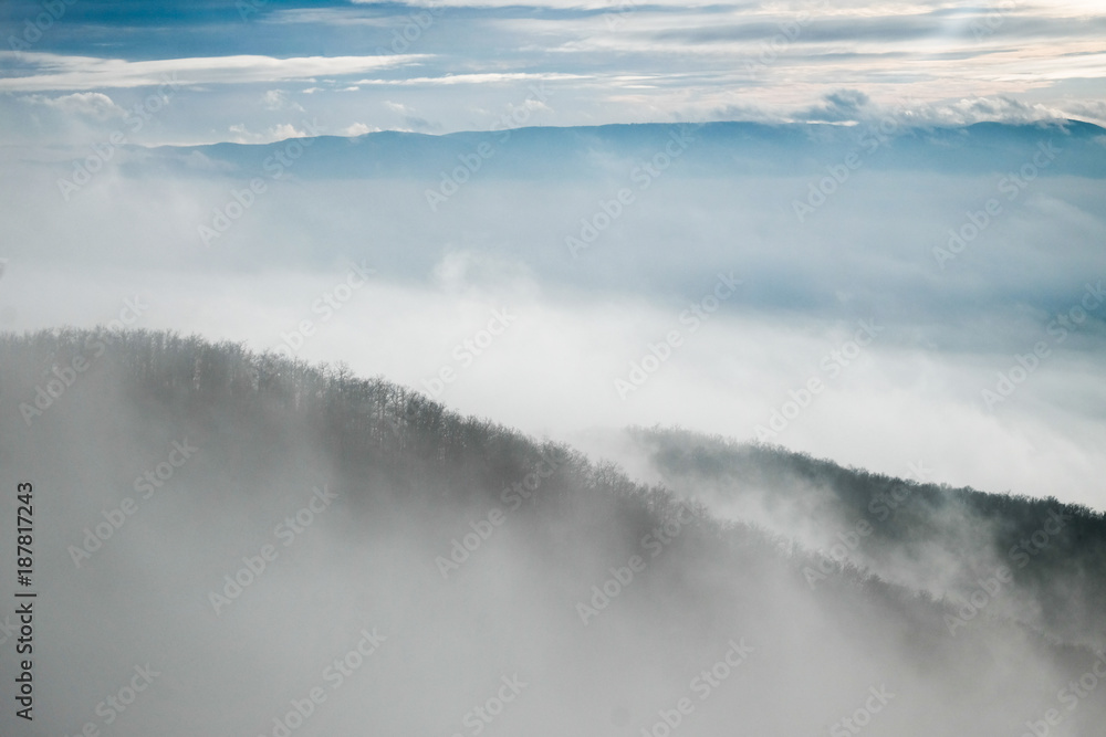 Fototapeta premium foggy mountain slope in winter with clouds and sunshine
