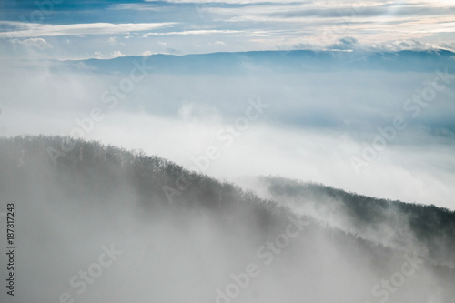 foggy mountain slope in winter with clouds and sunshine
