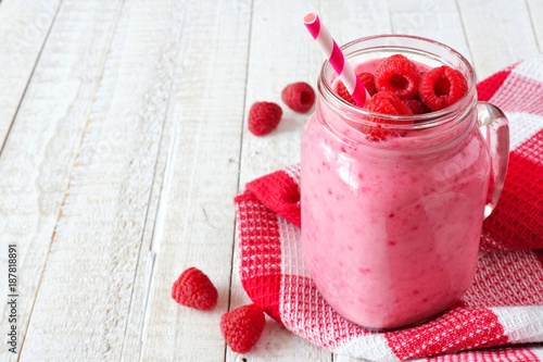Healthy raspberry smoothie in a mason jar glass, table scene, side orientation, against white wood