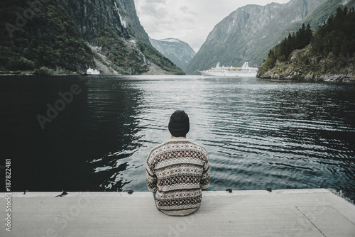 Caucasian man sitting on dock watching cruise ship photo