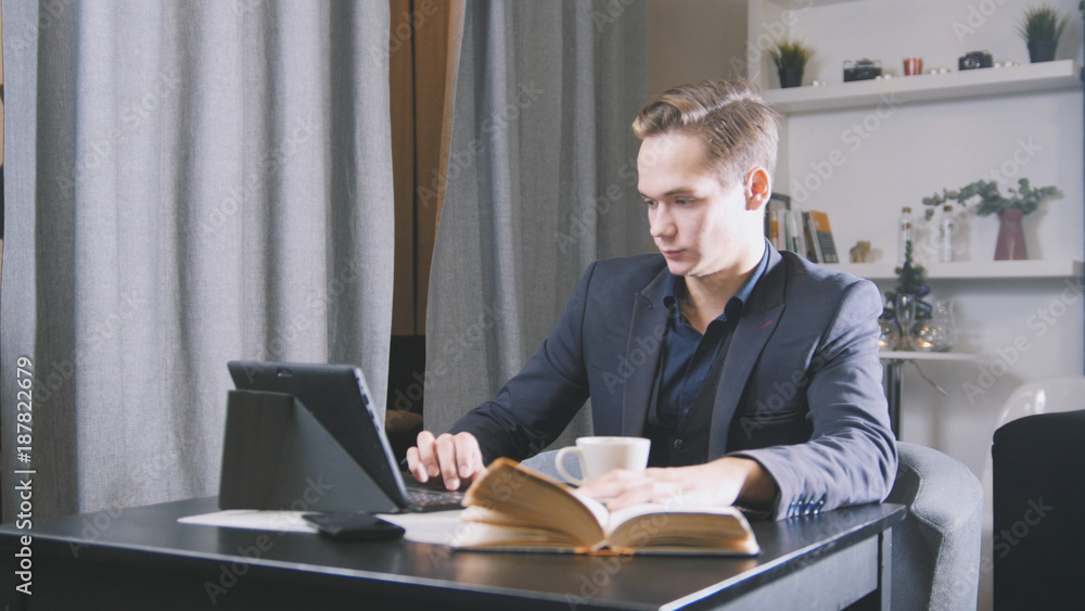 Young man sitting with notebook and book in cafe with coffee