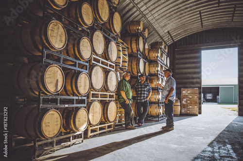 Men talking near barrels in distillery photo