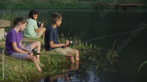 Kids at summer camp fishing in pond photo