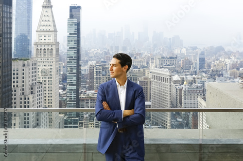 Caucasian businessman leaning on urban rooftop