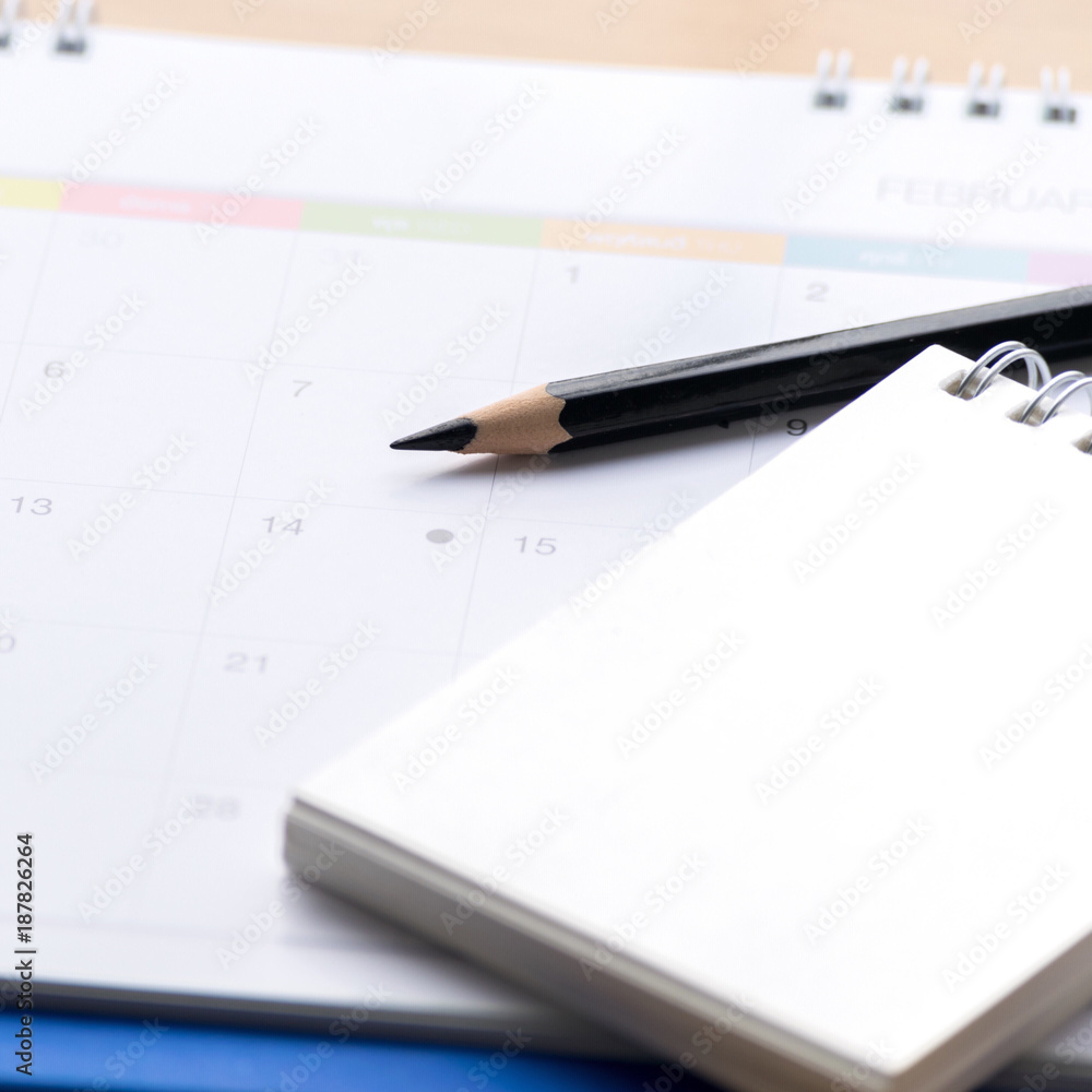 Notepad with pencil, calendar on wood board blurry background.using wallpaper for education, business photo.Take note of the product for book with paper and concept, object or copy space. Notepad with pencil, calendar on wood board blurry background.using wallpaper for education, business photo.Take note of the product for book with paper and concept, object or copy space.