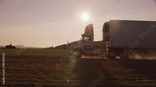 Semi truck driving down dusty road at sunset.  Fully released for commercial use. photo