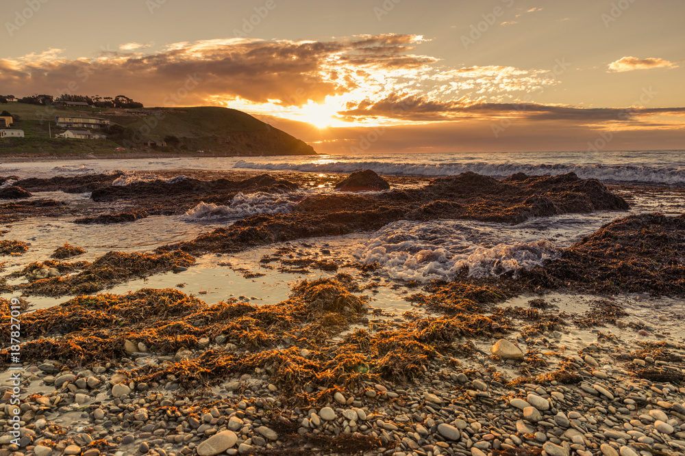 Obraz premium Colourful sunset at the beach with pebbles in Myponga Beach South Australia