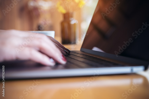 Closeup image of a business woman's hands working and typing on laptop keyboard on wooden table