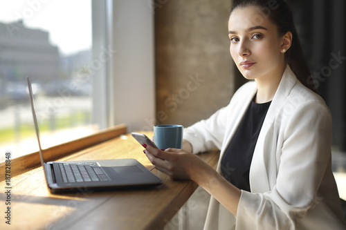 Caucasian woman texting on cell phone and drinking coffee photo