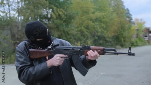 Armed man in black simulates shooting a machine gun. Bandit with weapons in hand. The criminal scene. Hands with a gun close-up