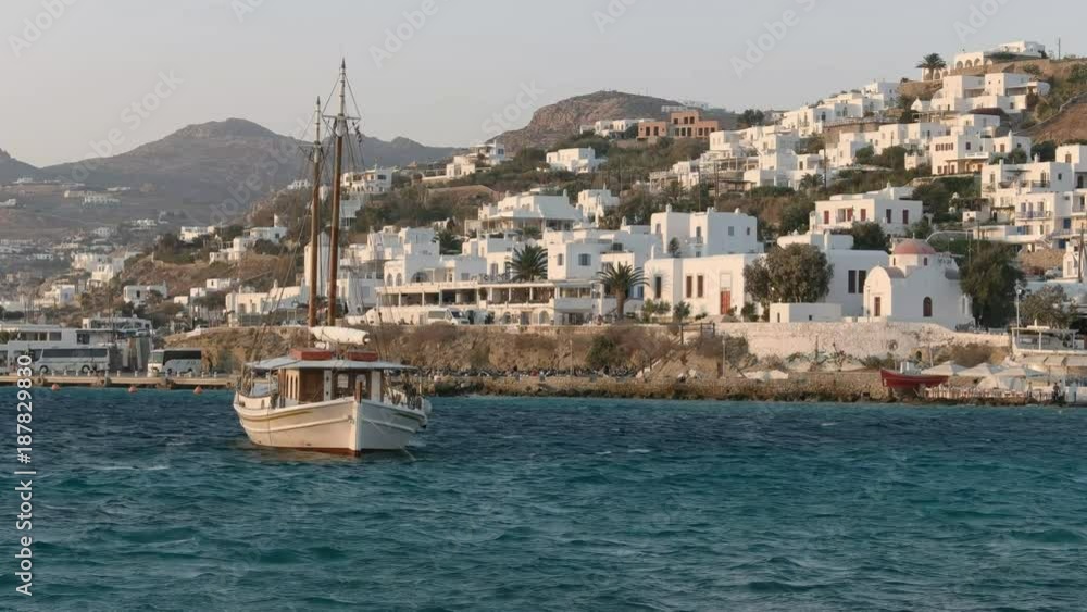 afternoon shot of a sailing boat and the view towards the new old port of chora, mykonos afternoon shot of a sailing boat and the view towards the new old port of chora, mykonos
