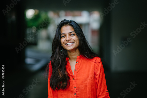 Portrait of attractive and young Indian woman smiling in an orange ethnic dress during the day