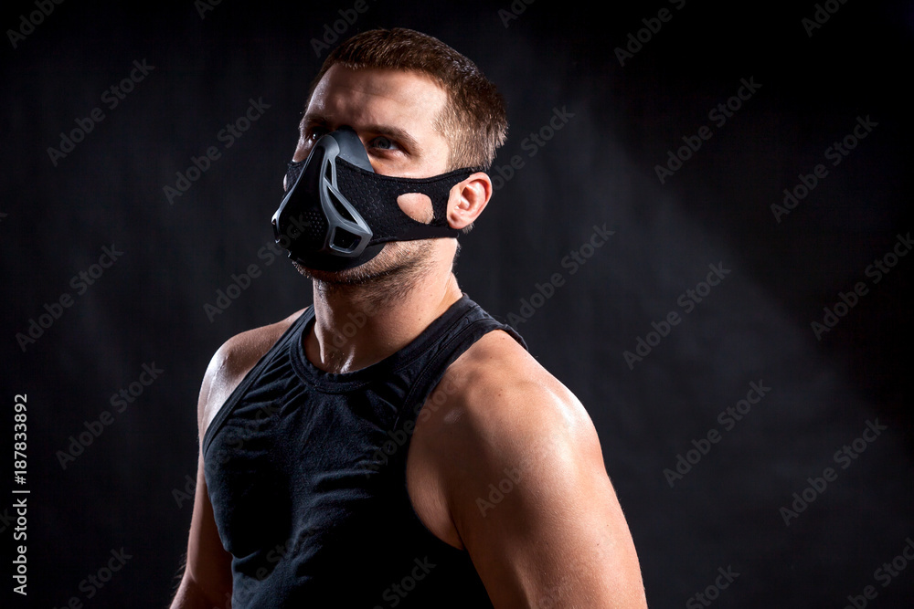 Portrait of young athletic man wearing sport shirt and training mask on black isolated background Portrait of young athletic man wearing sport shirt and training mask on black isolated background