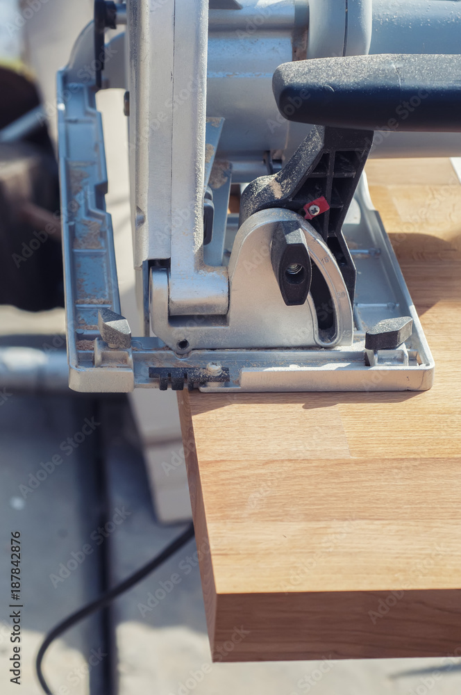 Close up electric saw to sawing wood board, solf focus.