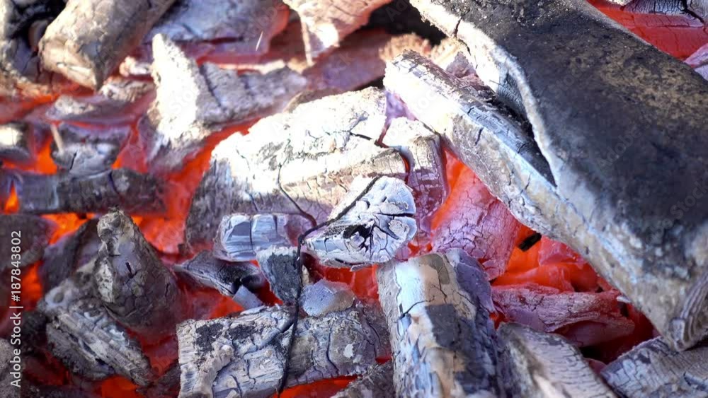 Smoldering fire close-up. Small flame on the coals and ash Smoldering fire close-up. Small flame on the coals and ash