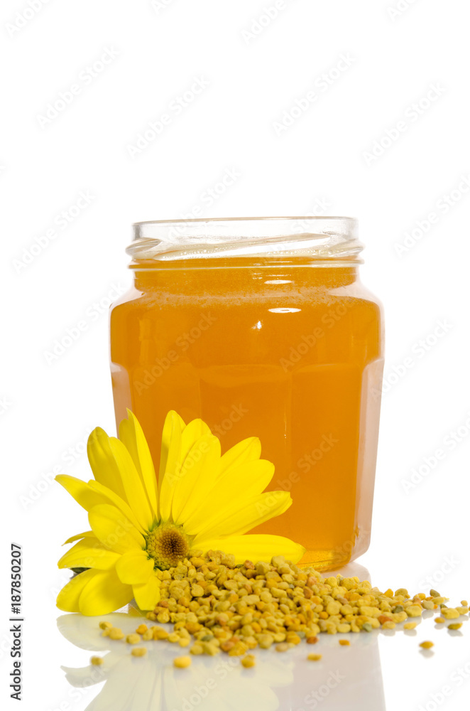 The jar of honey near a pile of pollen and flower isolated on white