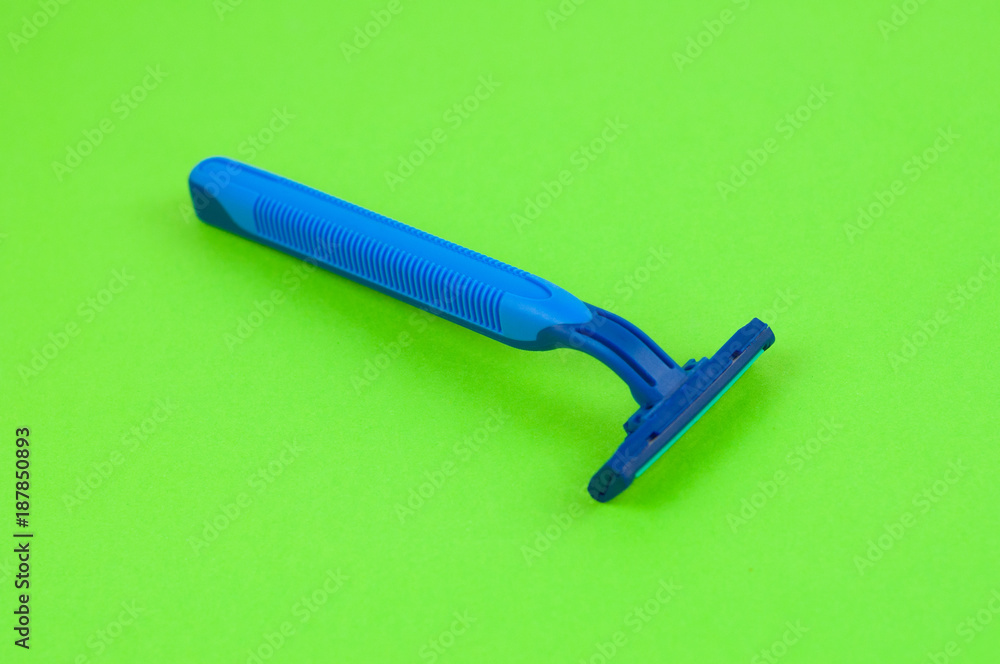 Single new blue plastic disposable razor with two blades on blank green paper Single new blue plastic disposable razor with two blades on blank green paper