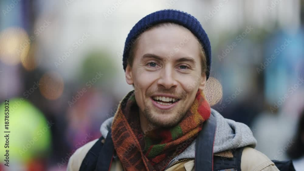 Happy young man with camera takes a photo of the viewer and talks cheerfully
