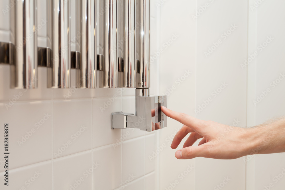 The man hand regulates thetemperature in the heated towel rail. The man hand regulates thetemperature in the heated towel rail.