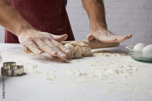 cropped image of chef rolling dough with rolling pin