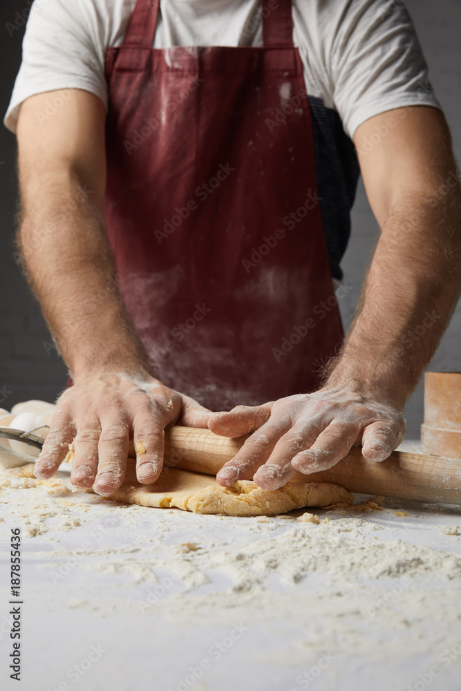 cropped image of chef kneading dough with rolling pin