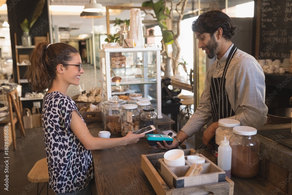 Customer making a mobile payment at counter Customer making a mobile payment at counter