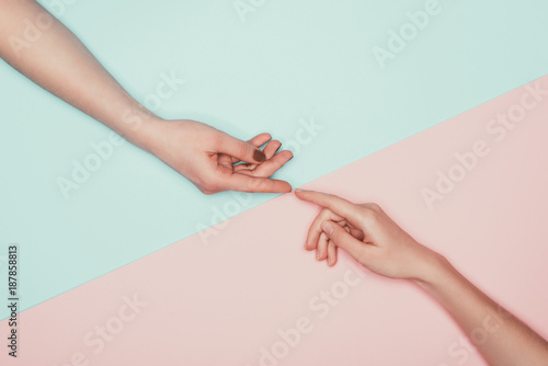 cropped shot of women touching fingers on halved pink and turquoise surface © LIGHTFIELD STUDIOS