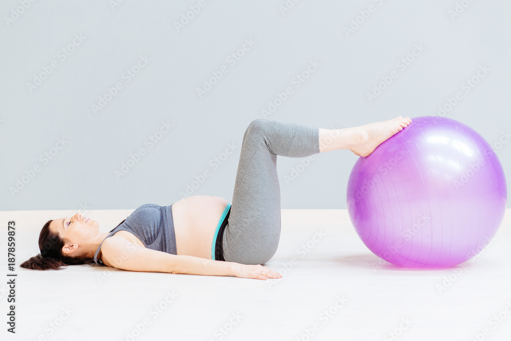 Pregnant woman in sportswear is doing exercises with gymnastic ball. Full body Pregnant woman in sportswear is doing exercises with gymnastic ball. Full body