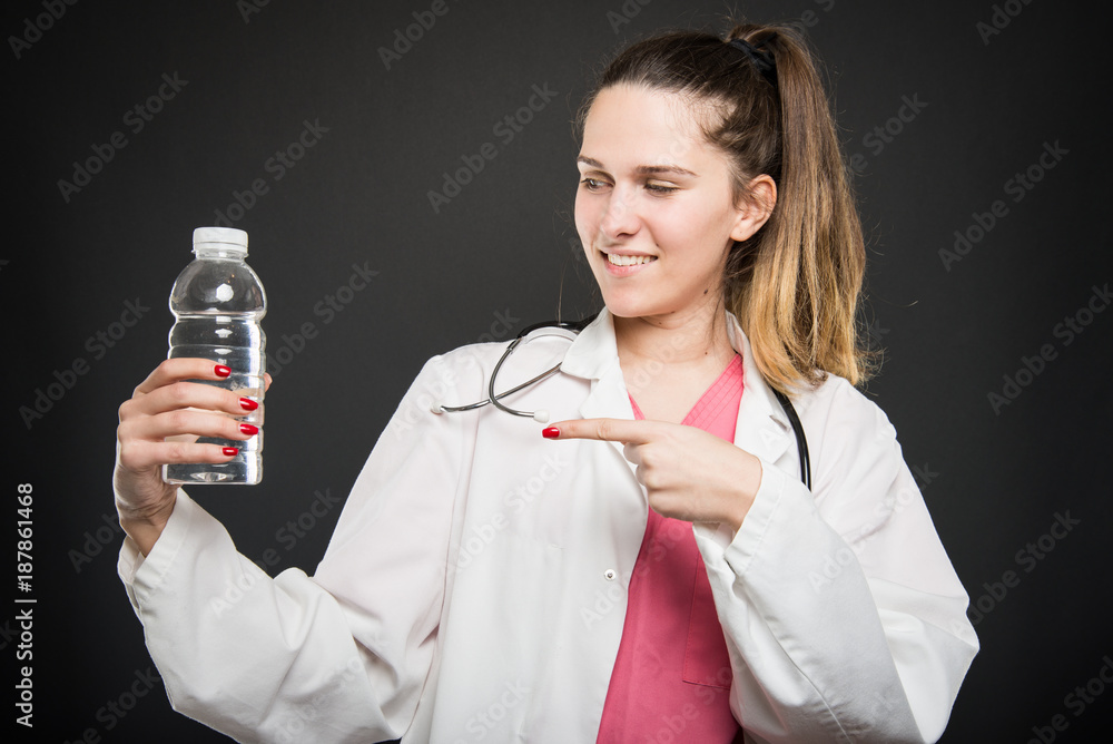 Female nutritionist pointing bottle of water and smiling Female nutritionist pointing bottle of water and smiling