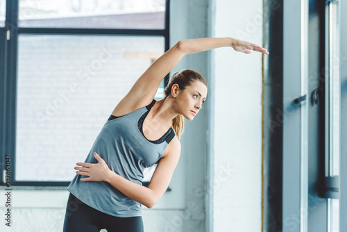 portrait of young sportswoman warming up before workout in gym