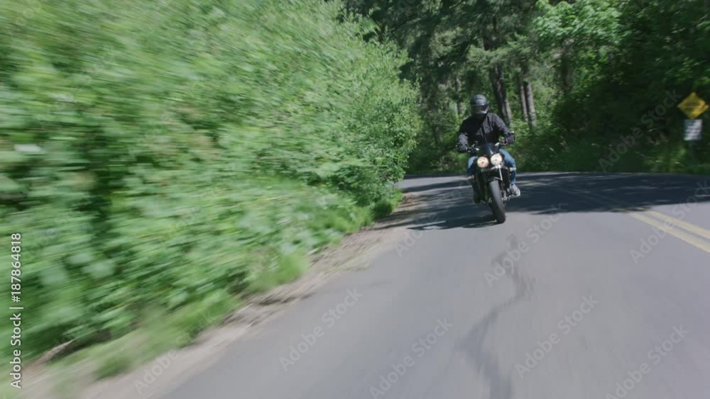 Tracking shot of man riding motorcycle on country road. Fully released for commercial use. Tracking shot of man riding motorcycle on country road. Fully released for commercial use.