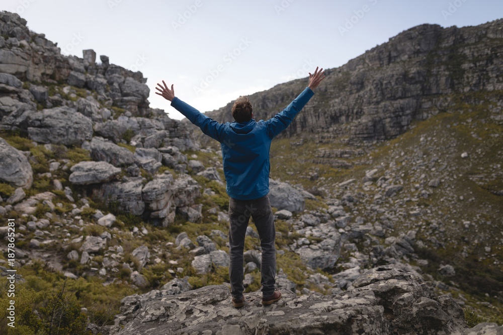 Hiker standing on rock with raised hands Hiker standing on rock with raised hands