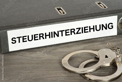 Handschellen und ein Ordner mit dem Aufdruck Steuerhinterziehung photo