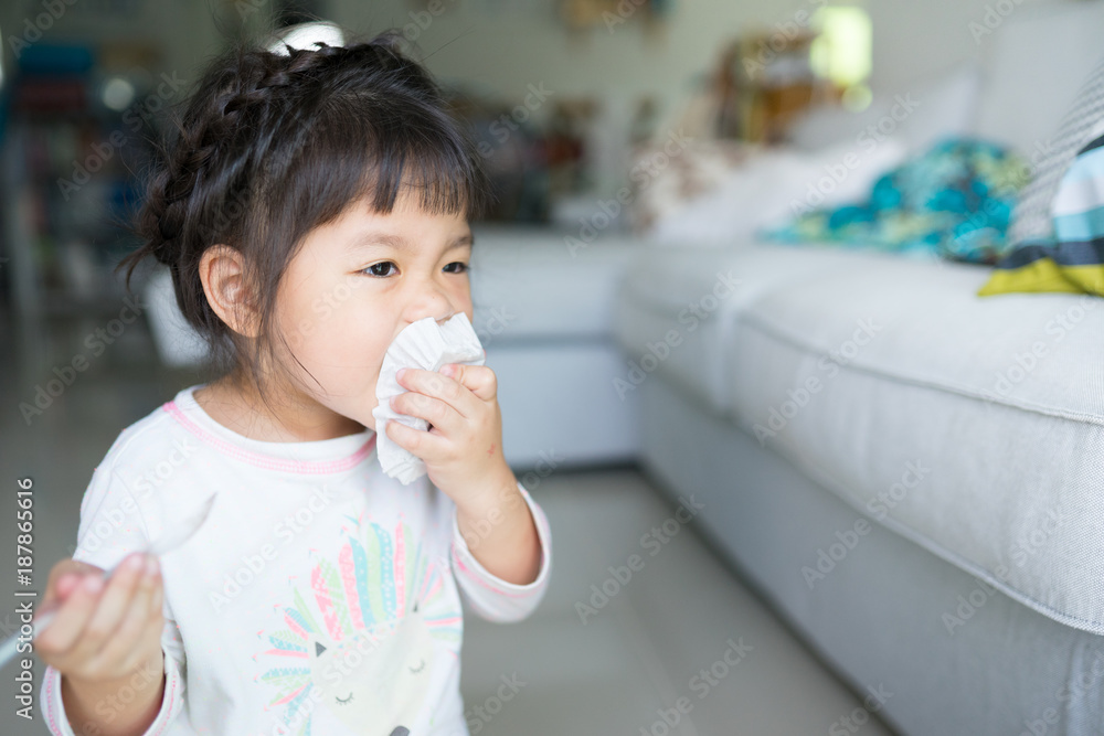 Happy Little asian girl eating brownie cake and she have spoon in her mouth in living room. Happy Little asian girl eating brownie cake and she have spoon in her mouth in living room.