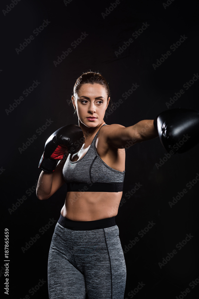 sporty athletic young woman boxing isolated on black