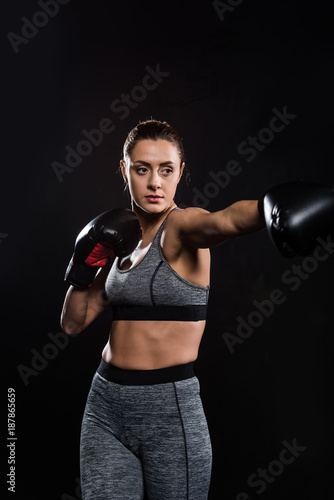 sporty athletic young woman boxing isolated on black © LIGHTFIELD STUDIOS