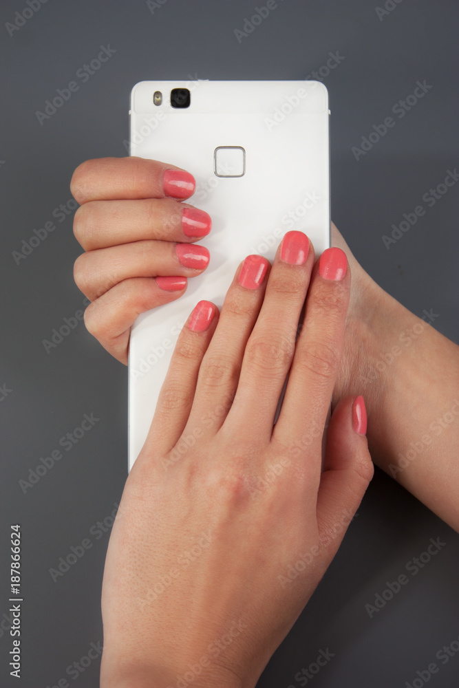 Women's beautiful, gentle hands hold a white phone. Gel-lacquer. Beautiful manicure of female hands Women's beautiful, gentle hands hold a white phone. Gel-lacquer. Beautiful manicure of female hands